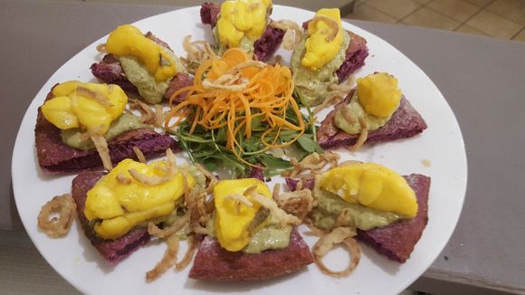 Antipasto servito su un piatto bianco con fette di tonno, bocconcini di mango e guarnizione di carote grattugiate.