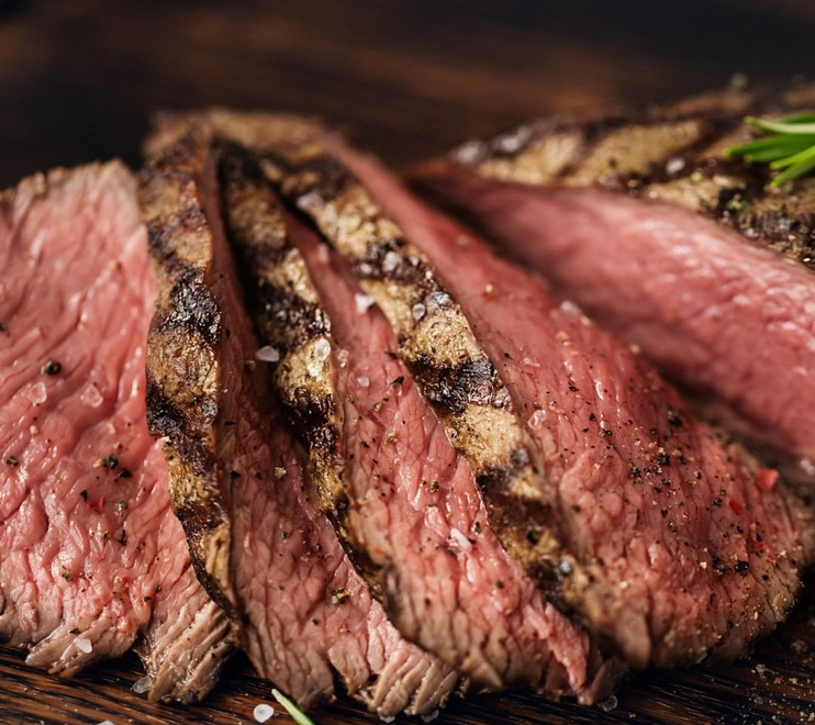 Fettine di bistecca al sangue con crosta pepata su un tagliere scuro