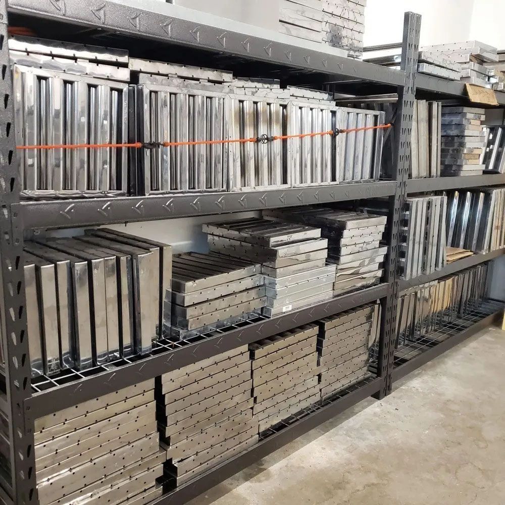 Metal shelving unit packed with stacks of rectangular metal panels. Warehouse setting.