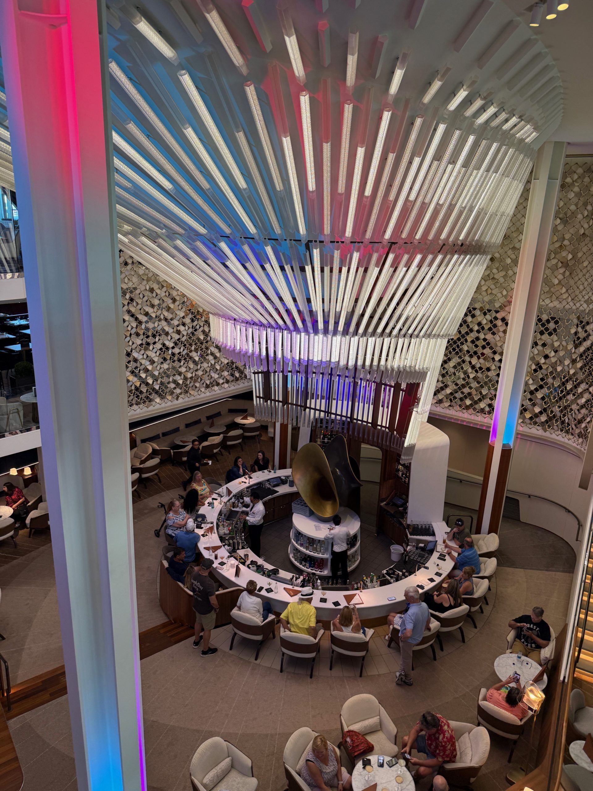 Circular restaurant seating beneath a colorful canopy, with diners around a central display or sculpture.