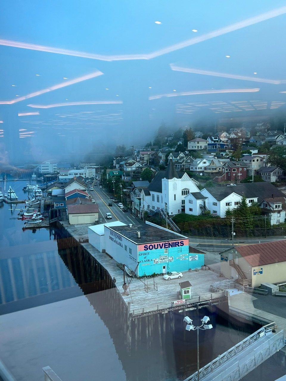 Foggy waterfront neighborhood with houses, docks, and reflections on calm water at dusk