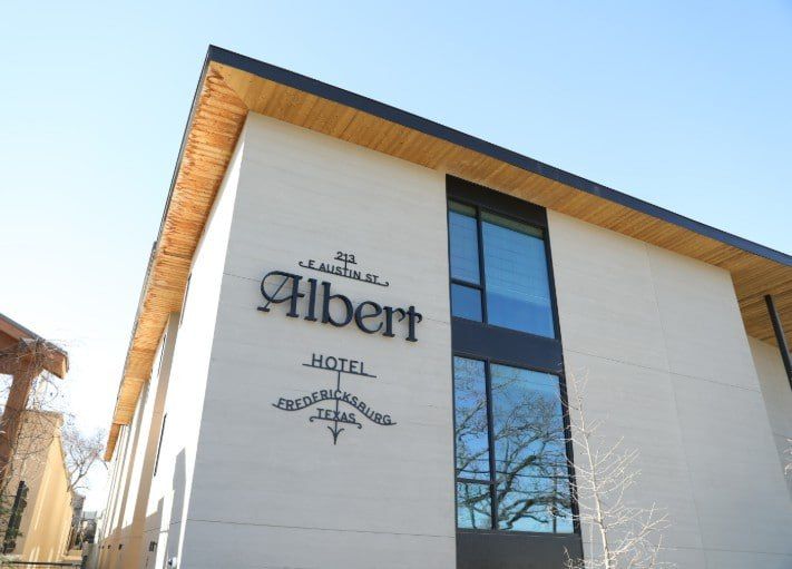 Hotel Albert exterior with white facade, wood roof trim, and blue-tinted windows under a clear sky
