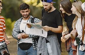 Group of people outdoors reading a map together on a sunny day