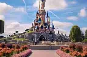 Disney castle with pink flowers in the foreground and a blue sky overhead