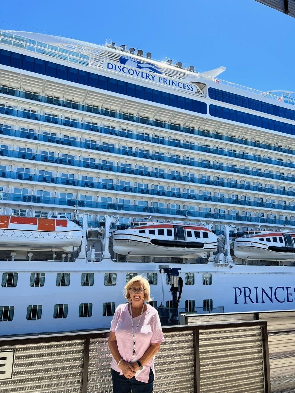 Woman standing before a large Princess cruise ship docked at port