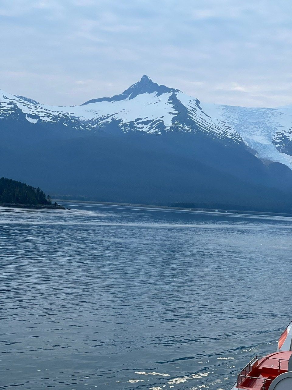 Snow-capped mountain over a calm blue lake, with a red boat at the lower right.