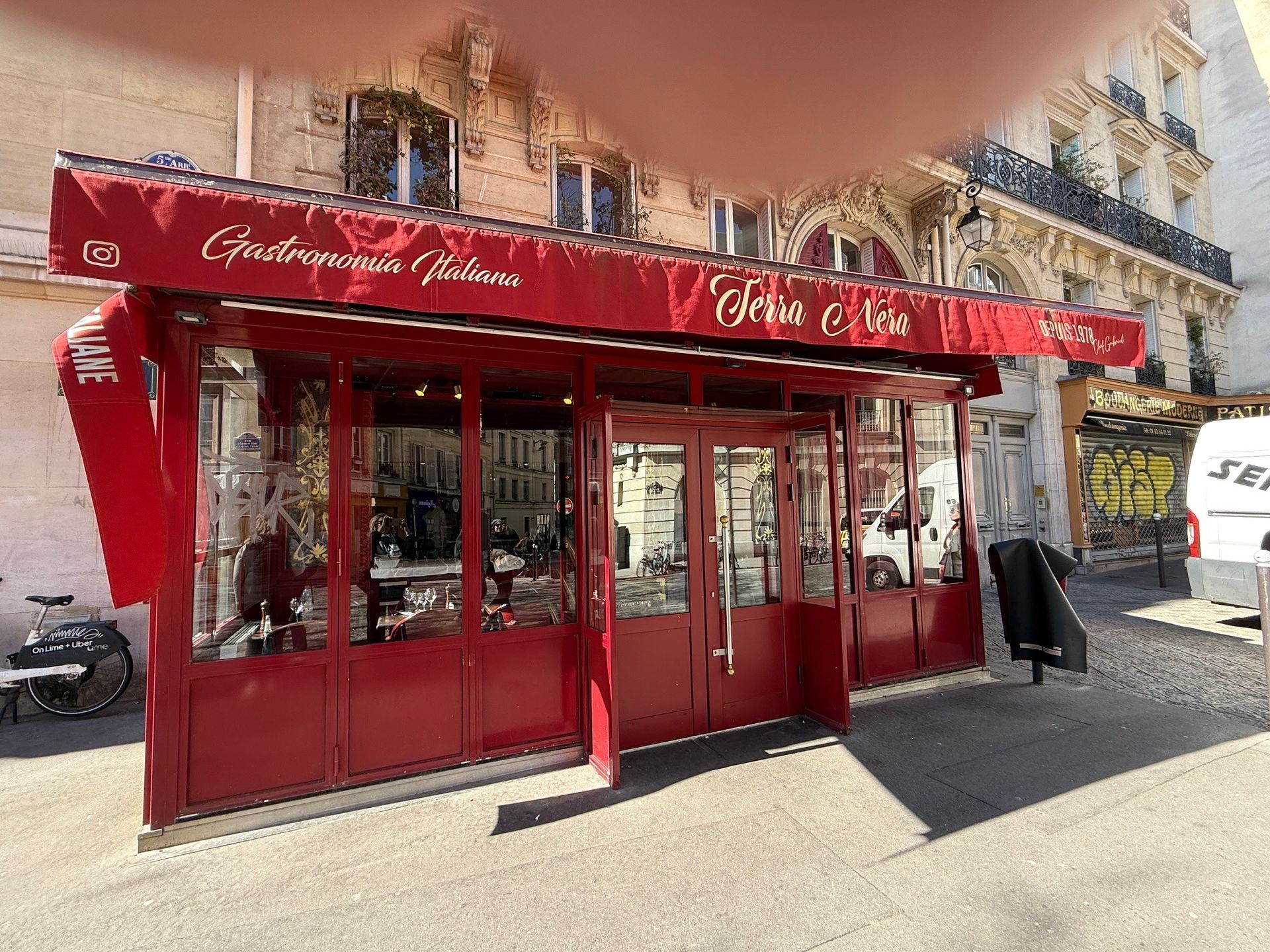 Red storefront café with red awning and glass windows on a sunny street corner
