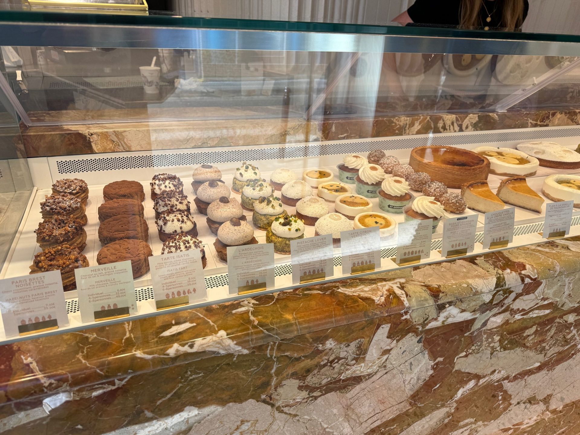 Bakery display case with assorted pastries and donuts on trays behind glass.
