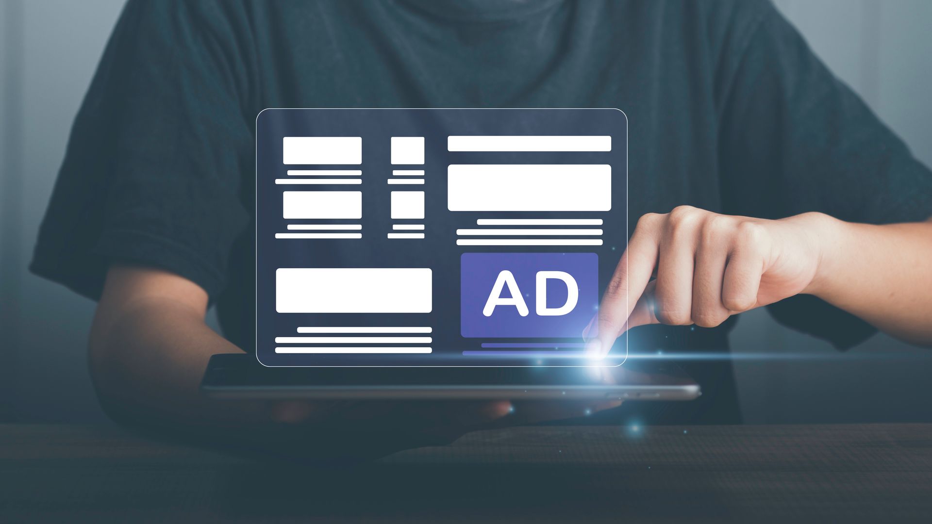 A person is using a tablet with an ad icon on the screen.