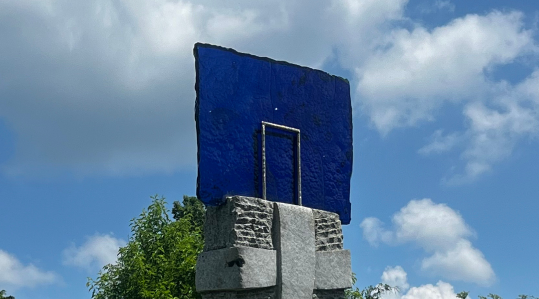 Blue glass atop a stone on sculpture titled 