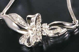 Silver floral necklace with sparkling clear gemstones on a black background