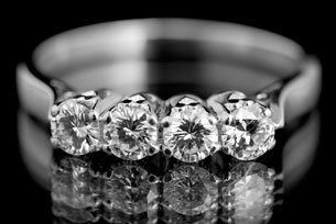 Five-stone diamond ring on a reflective black surface