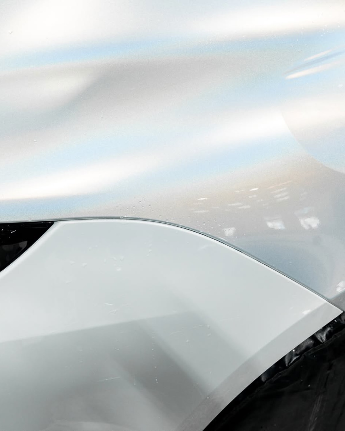 Close-up of a white car’s front fender and wheel arch.