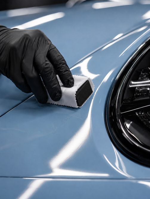 Gloved hand holding a small white car model over a glossy black surface