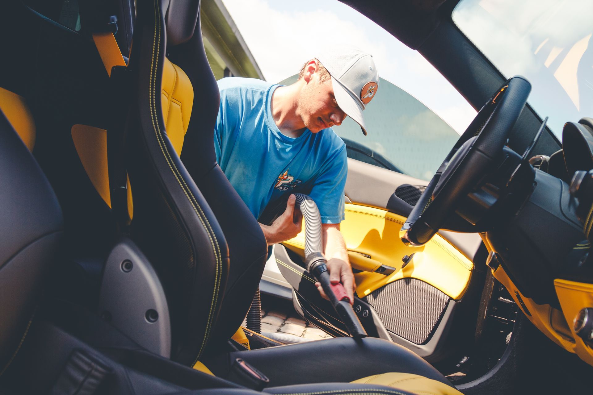 Man cleaning the interior of a yellow sports car with the door open