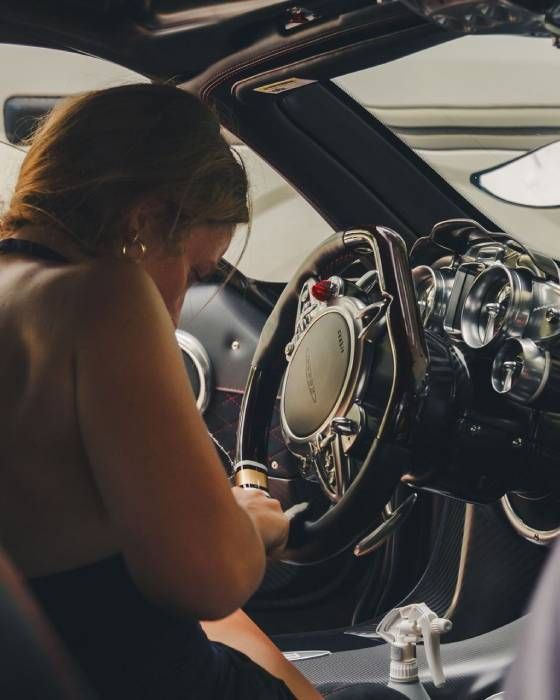 Person sitting in a sports car cockpit, adjusting controls near the steering wheel.