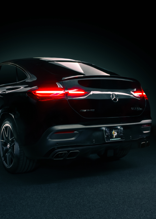Rear view of a black luxury SUV with red taillights glowing in a dark studio setting