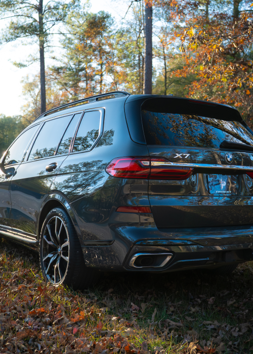 Dark blue SUV parked on a leaf-covered forest path in autumn