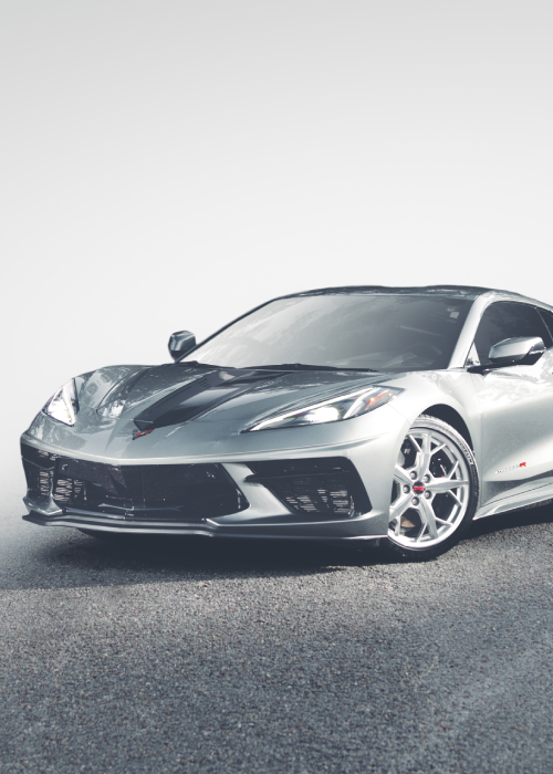 Silver sports car on a road, front-left view, with sleek low-profile styling and alloy wheels.
