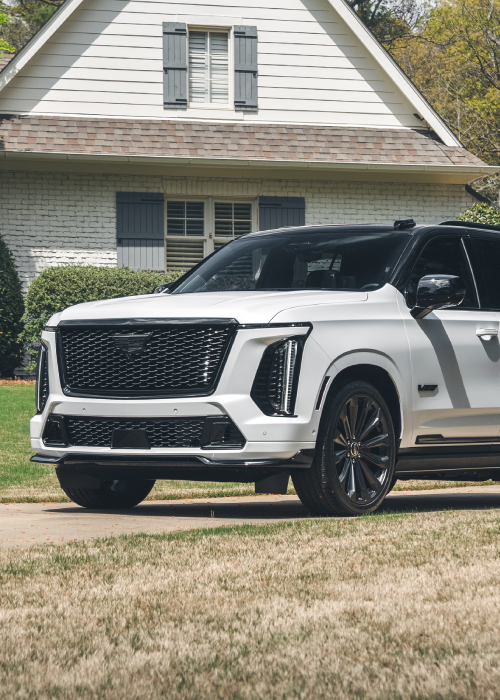 White and black luxury SUV parked on a lawn in front of a house