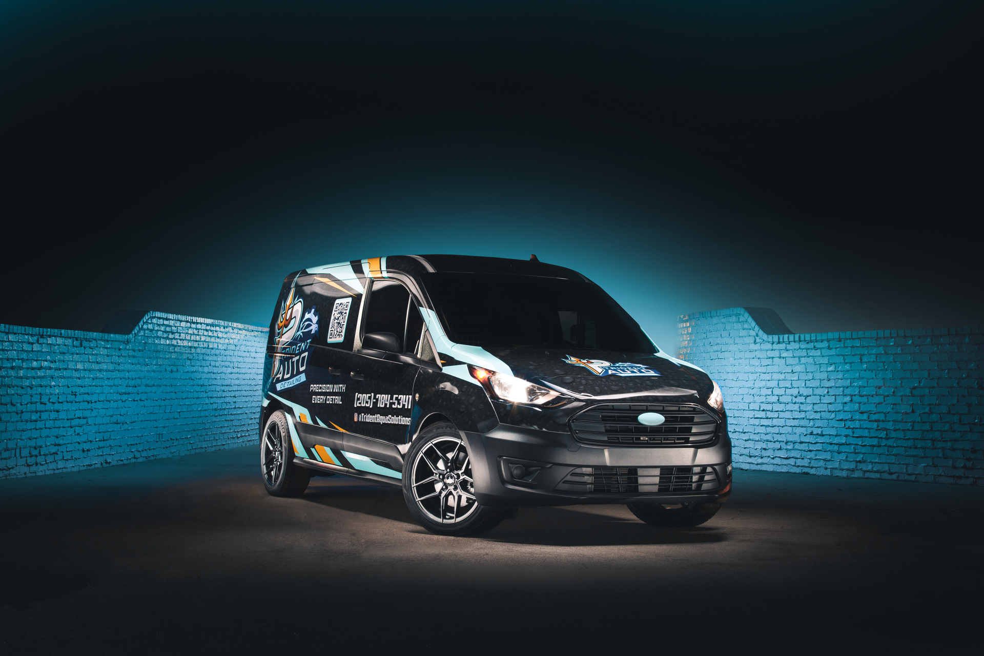 Black compact cargo van on a dark studio floor with a blue textured background