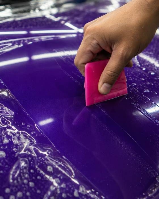 Hand smoothing glossy purple paint with a pink squeegee