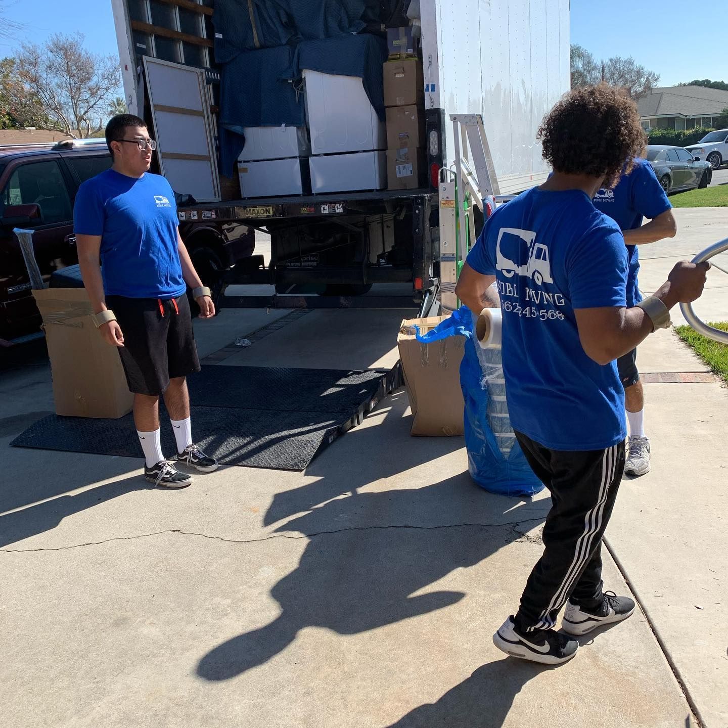 People unloading boxes from a moving truck on a sunny street