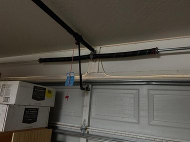 Garage ceiling with exposed pipes, black insulation, and a blue hanging item near the overhead door track