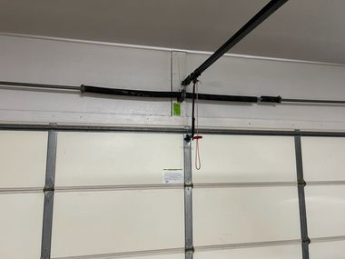 Garage door with horizontal panels and an overhead opener rail, viewed from inside the garage.