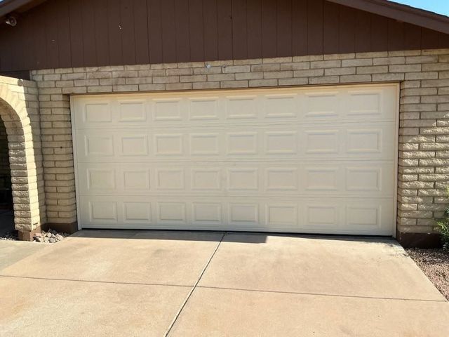 White double garage door on a brick house with a concrete driveway in front.