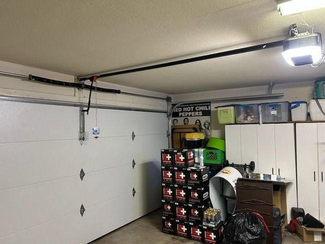 Garage with closed white door, stacked boxes, and assorted tools and storage items.