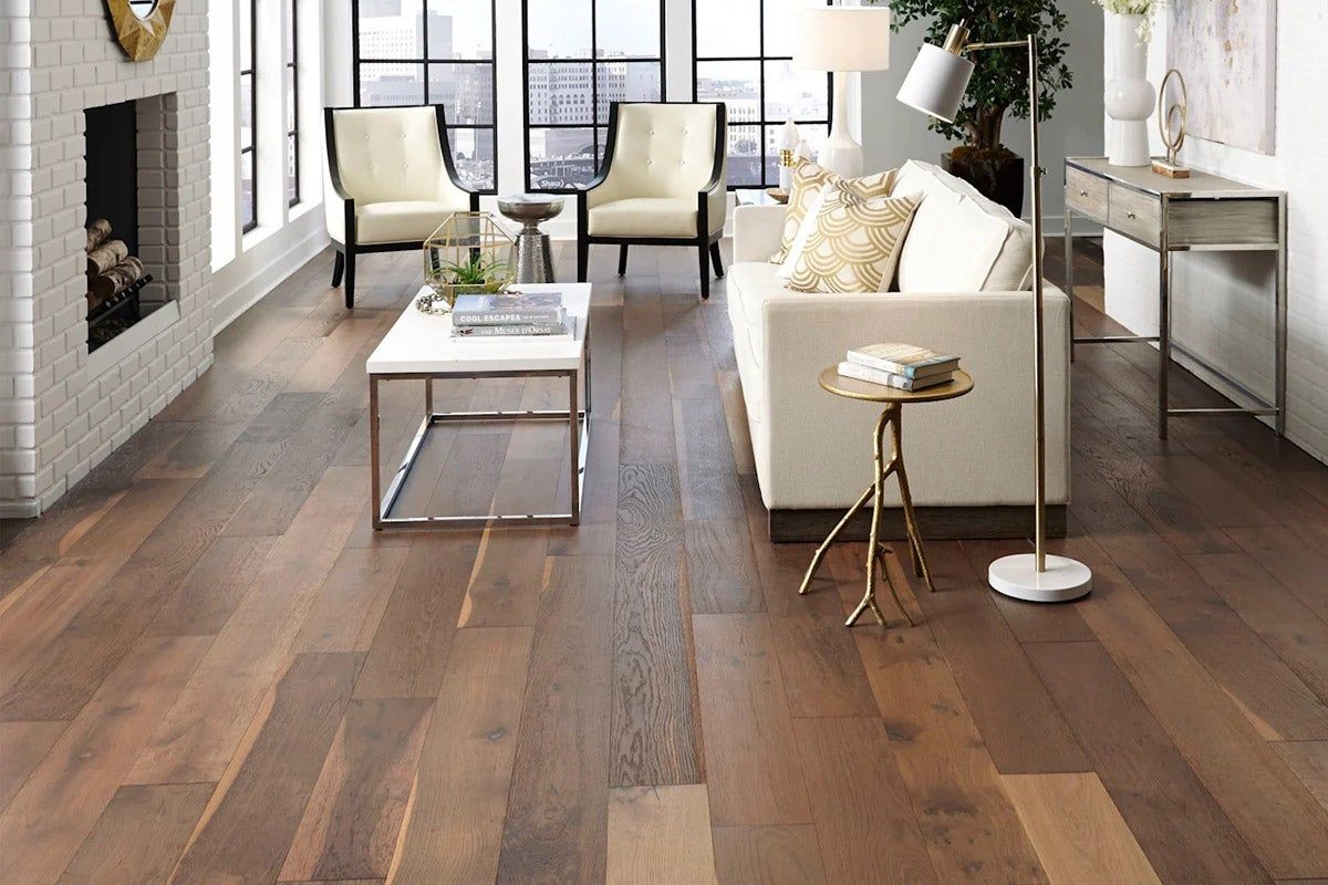 Laminate flooring in a living room with white couch and glass coffee table