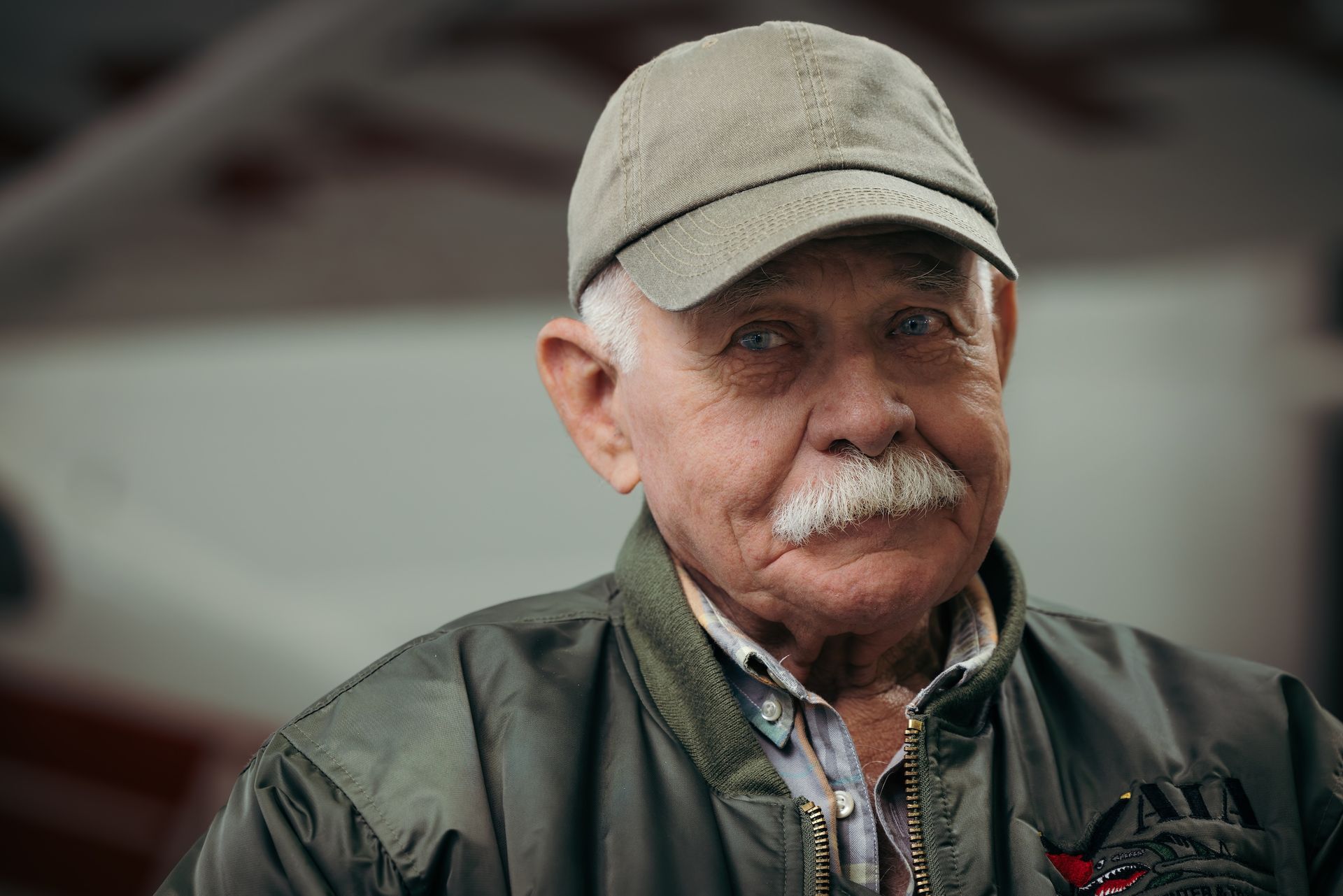 The man is wearing a hat and a jacket and has a mustache.