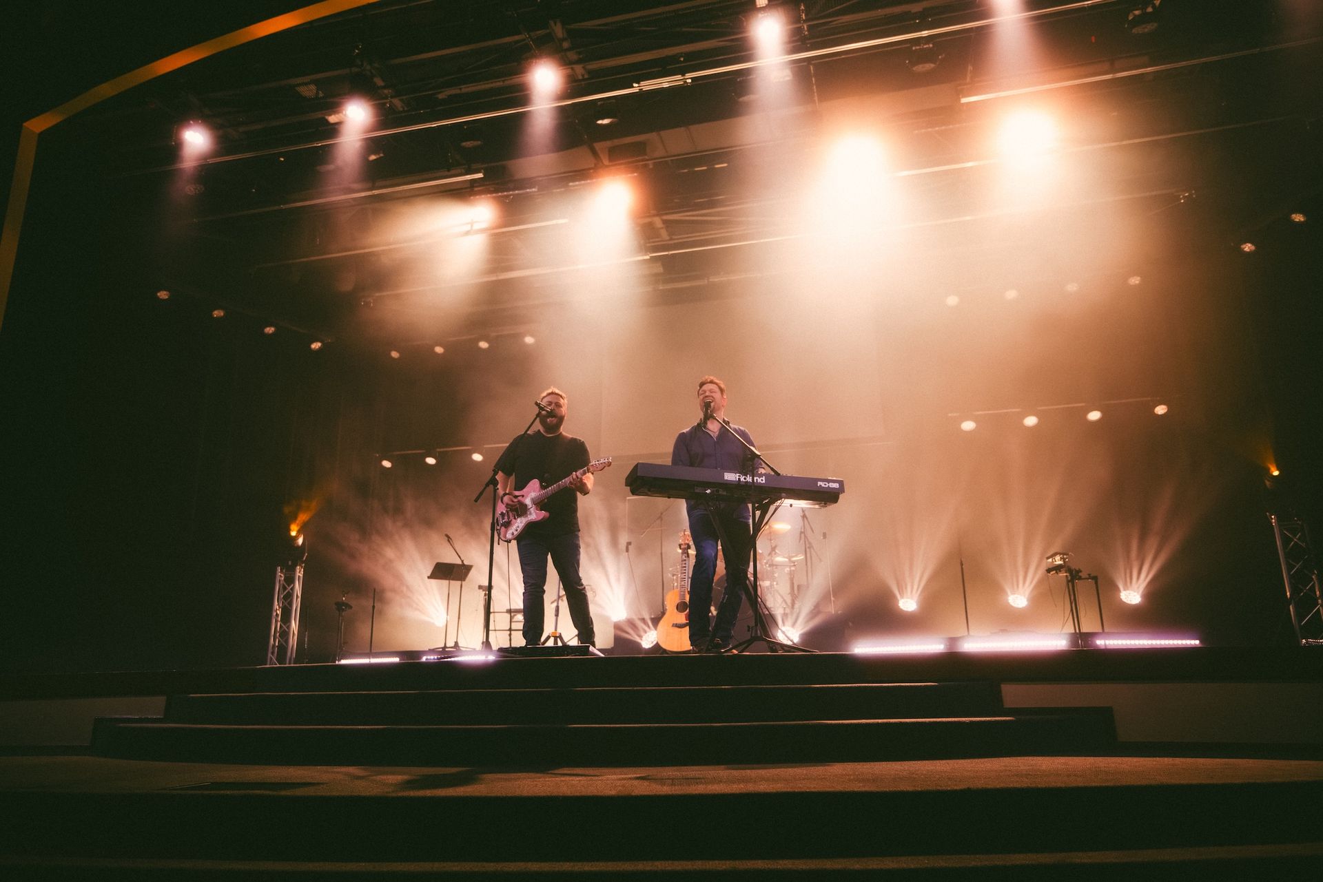 Two men are playing instruments on a stage at a concert.