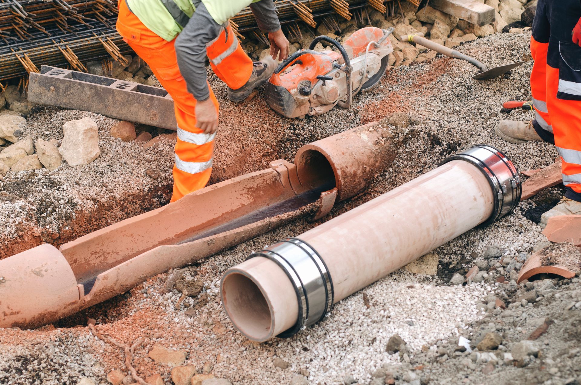 Workers handle large rusted and white pipes at a roadside construction site Workers handle large rusted and white pipes at a roadside construction site