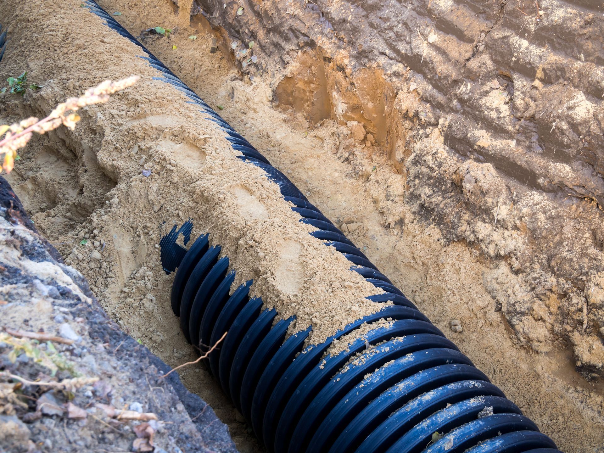 Blue corrugated pipe in a muddy trench with dirt and concrete edges Blue corrugated pipe in a muddy trench with dirt and concrete edges