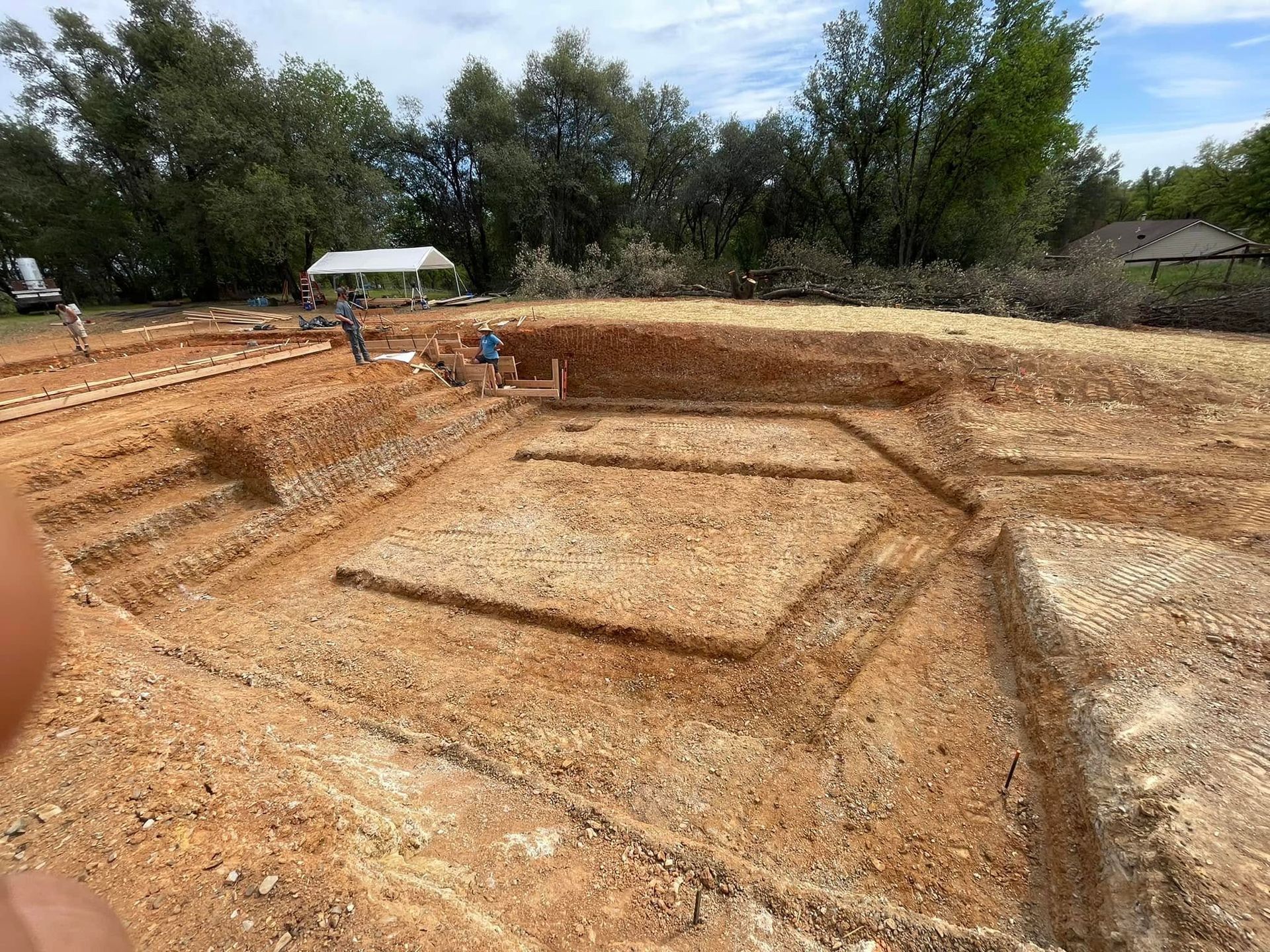 Archaeological excavation site with rectangular trenches in a dry, open field under trees. Archaeological excavation site with rectangular trenches in a dry, open field under trees.