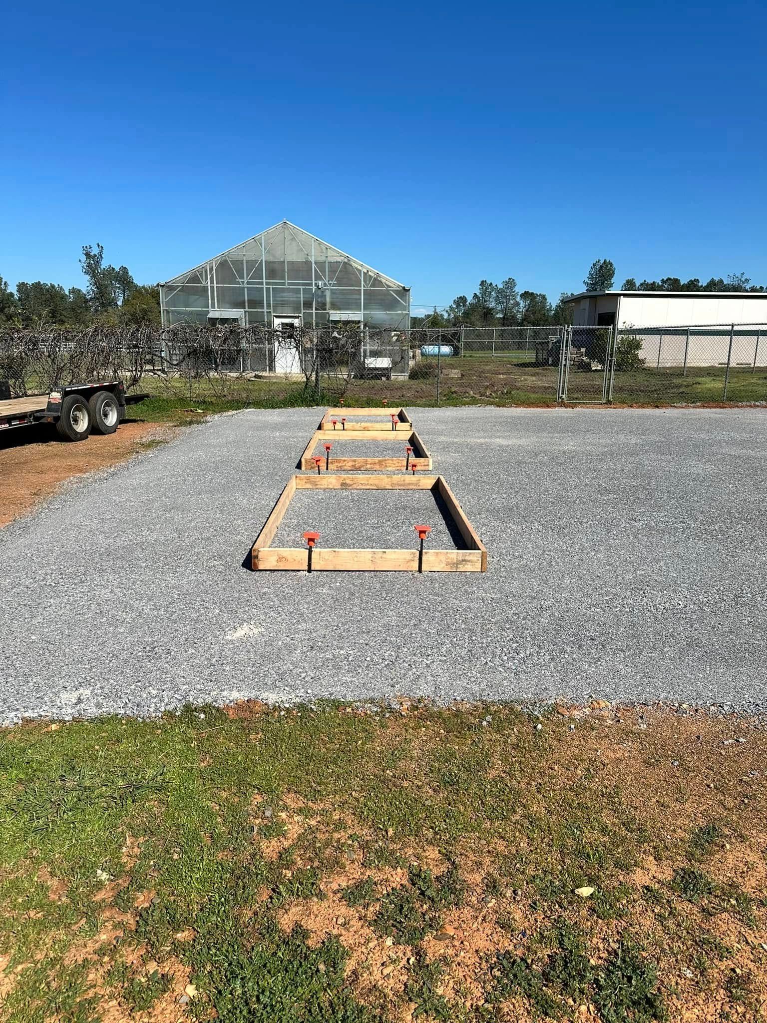 Gravel path leading to a greenhouse under a clear blue sky, with grass and landscaping in front. Gravel path leading to a greenhouse under a clear blue sky, with grass and landscaping in front.