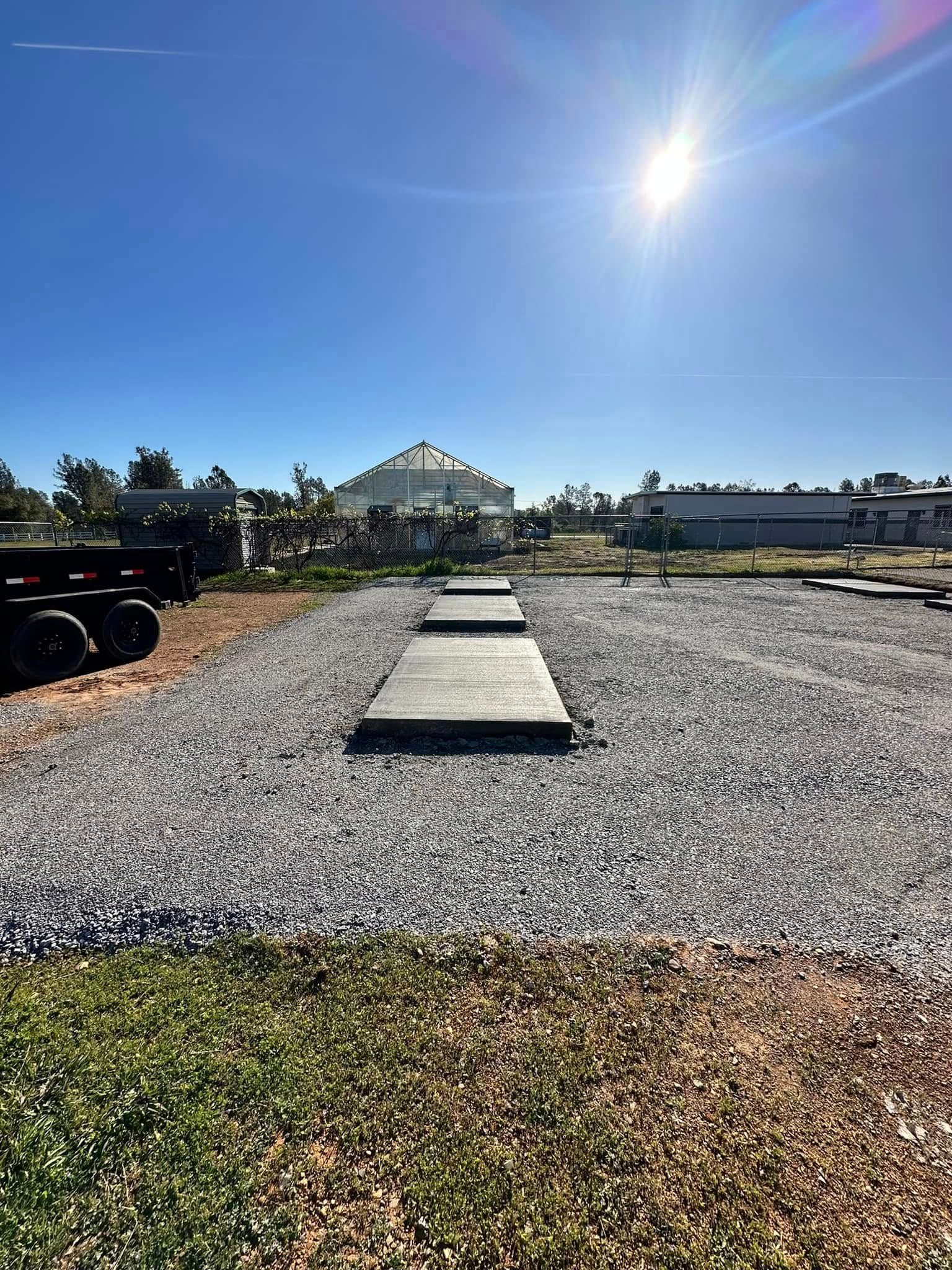 Gravel path with concrete stepping stones leading toward a greenhouse under a bright sun Gravel path with concrete stepping stones leading toward a greenhouse under a bright sun
