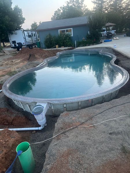 Backyard swimming pool with concrete deck, near a house and RV at dusk Backyard swimming pool with concrete deck, near a house and RV at dusk