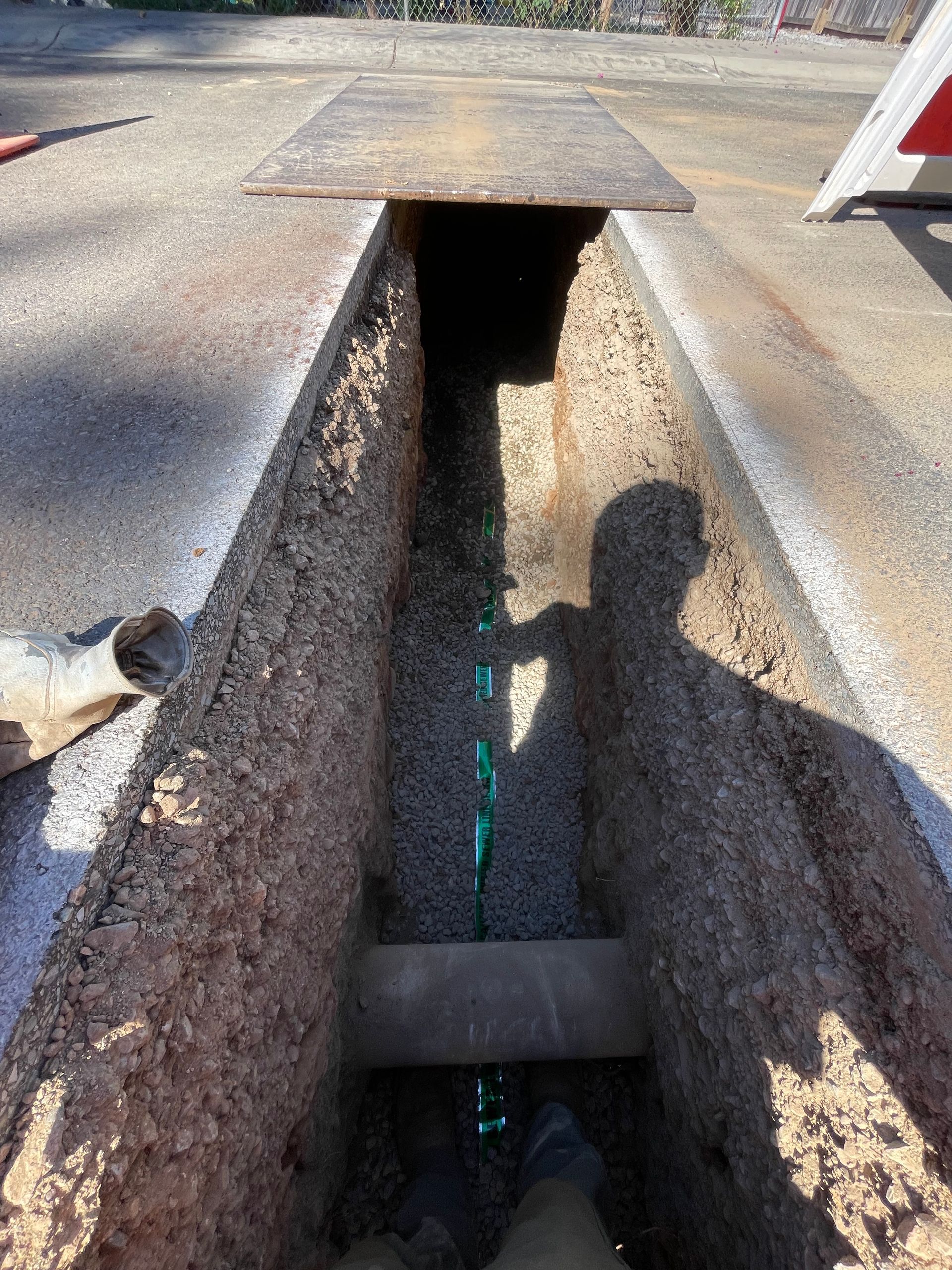 Gray PVC pipe running through a rough orange-brown trench in the ground Gray PVC pipe running through a rough orange-brown trench in the ground