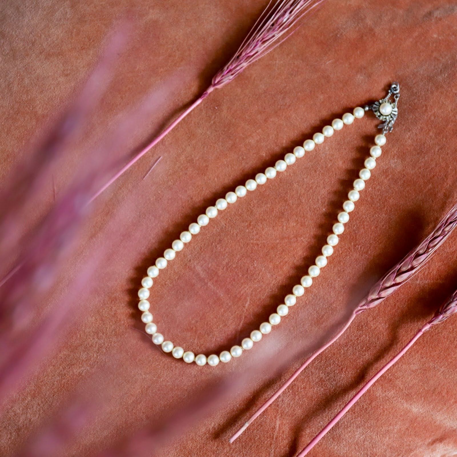 Parelketting op roze satijn met een zilveren sluiting.