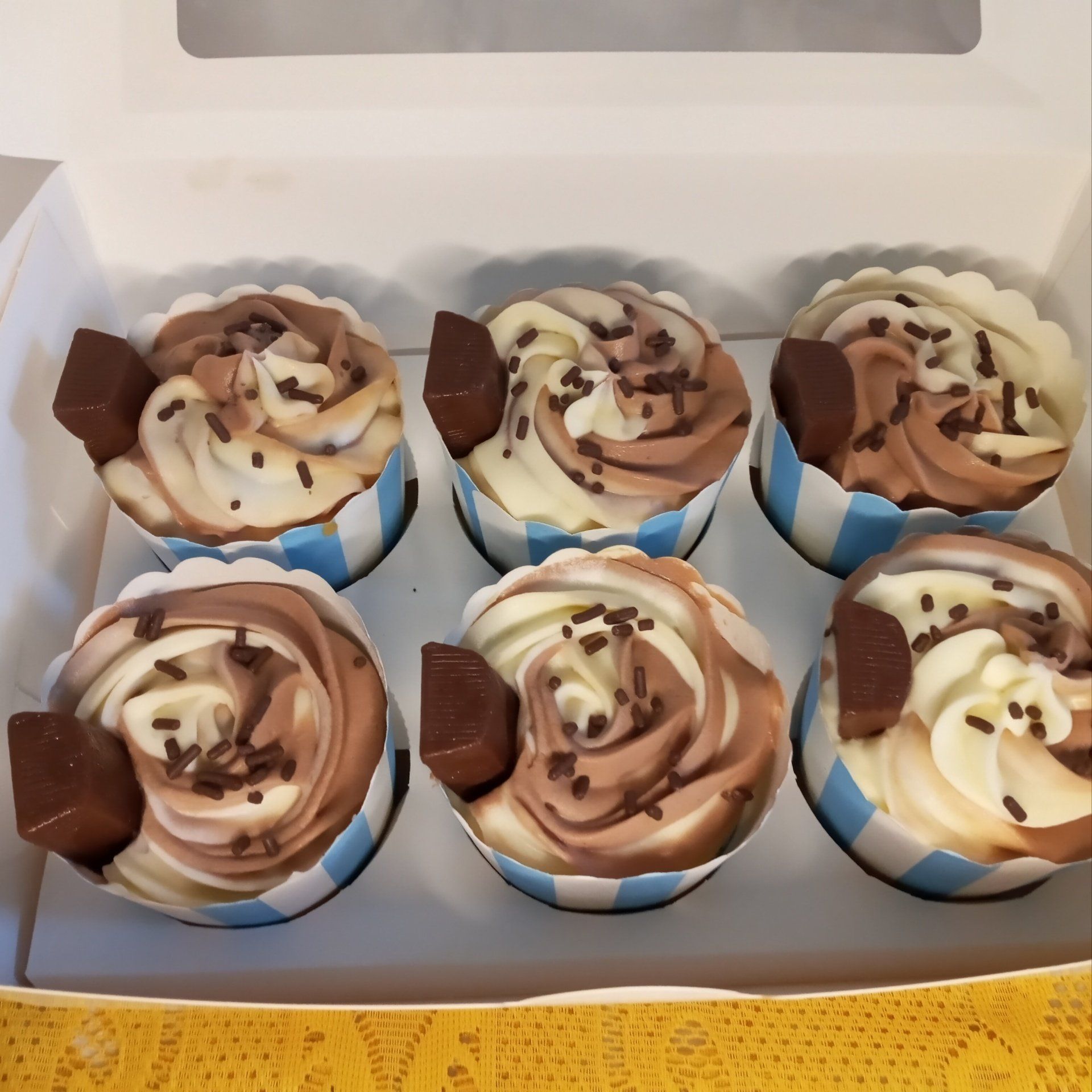 A box of cupcakes with chocolate frosting and sprinkles
