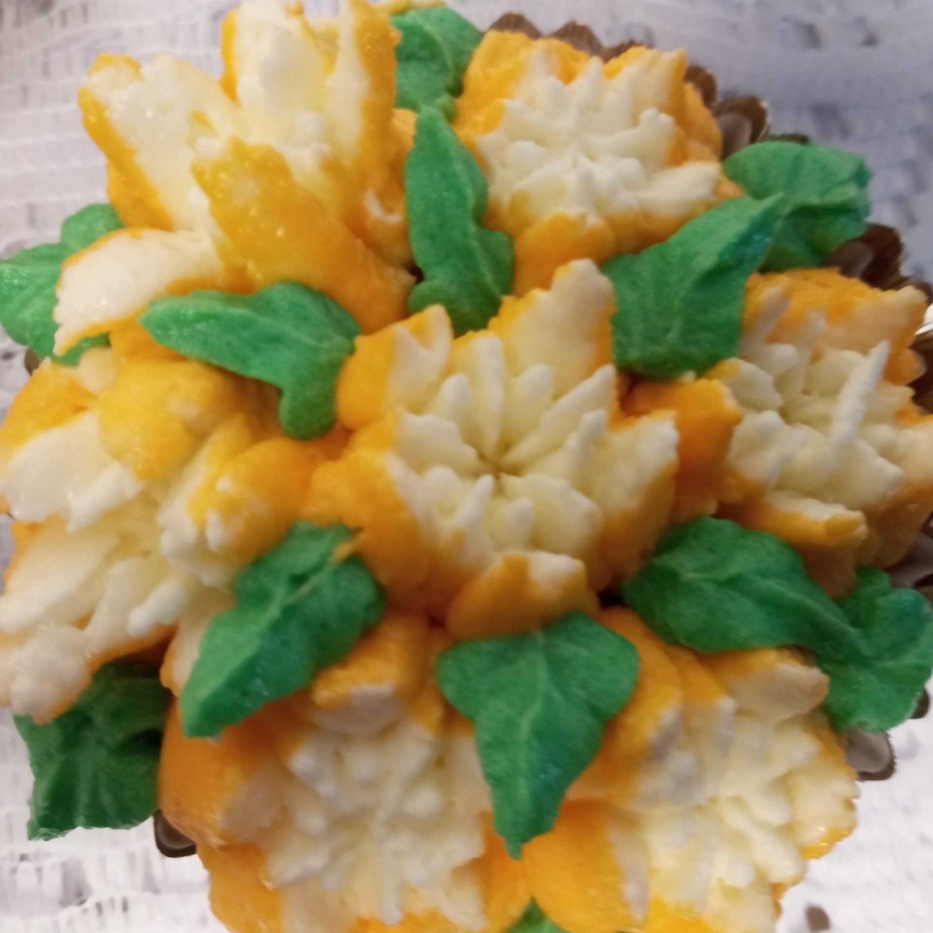 A cupcake with yellow and white frosting and green leaves