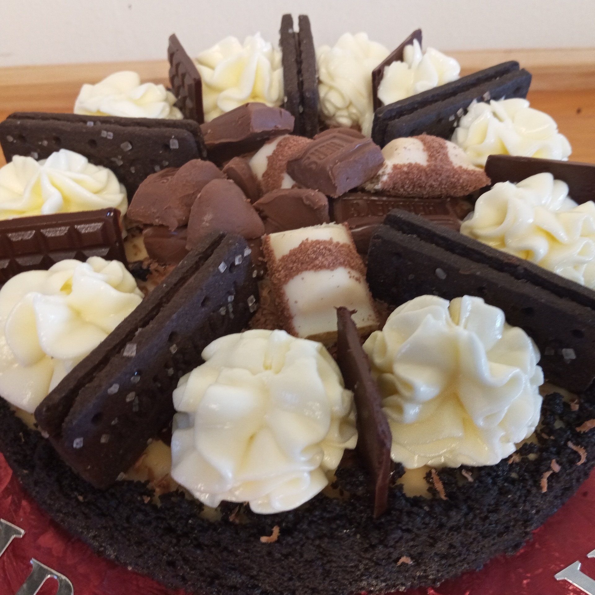 A chocolate cake with whipped cream and chocolate pieces