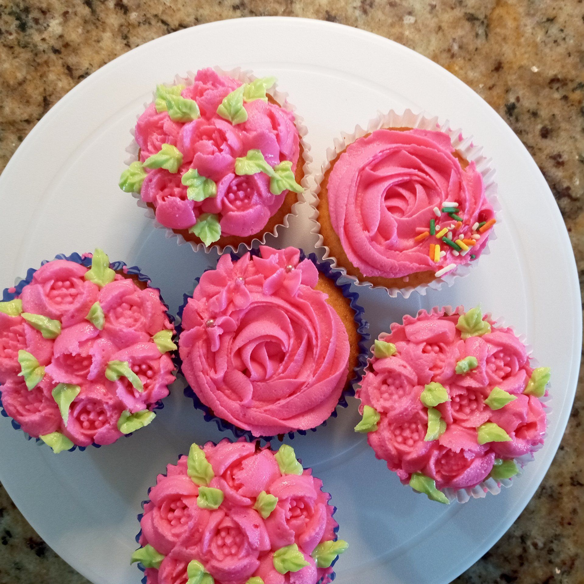 The cupcakes are decorated with pink frosting and green leaves