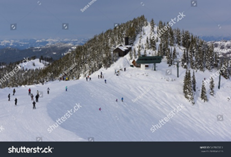 Snowy mountain with skiers; lift, trees, and buildings visible.