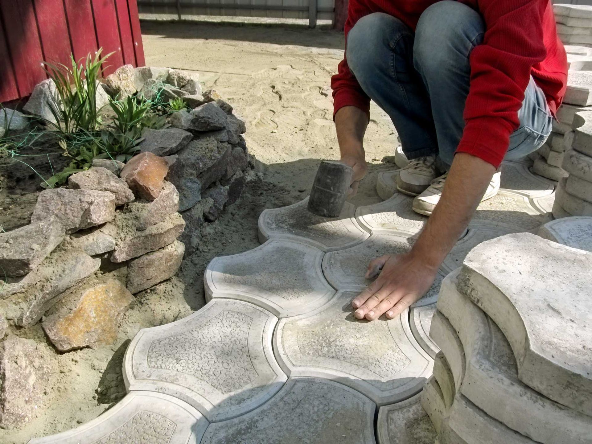 A paved pathway winds through a wooded area with gravel shoulders on both sides, framed by trees and dense greenery.