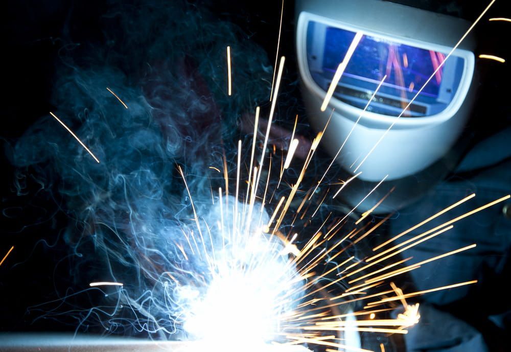 A Man Wearing a Welding Helmet is Welding a Piece of Metal — Riverside Aluminium & Stainless in Coolongolook, NSW