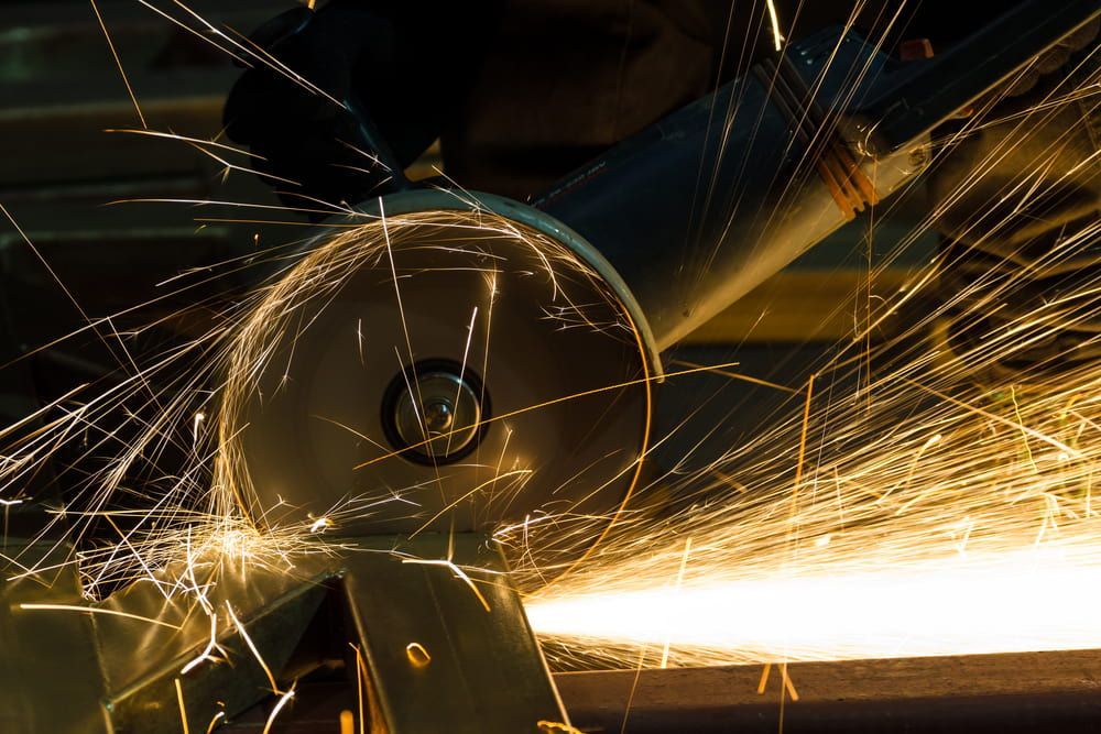 A person is using a grinder to cut a piece of metal — Riverside Aluminium & Stainless in Coolongolook, NSW